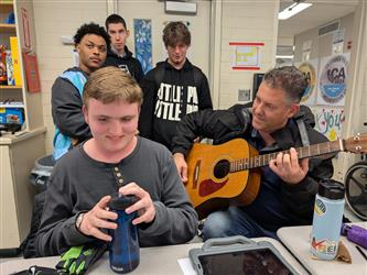 teacher playing the guitar for students