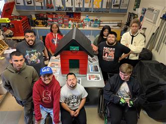 Students surround a birdhouse made in woodshop